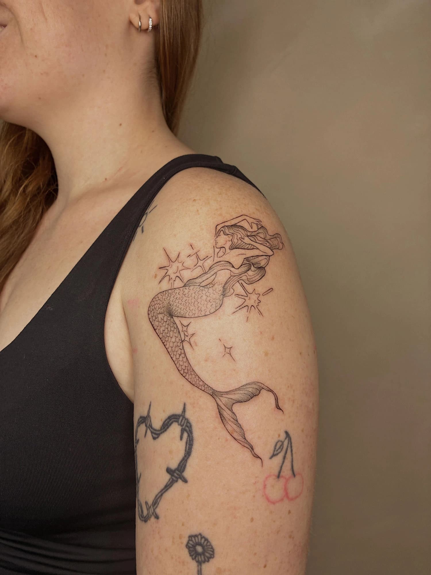 Tatuaje sirena línea fina en brazo