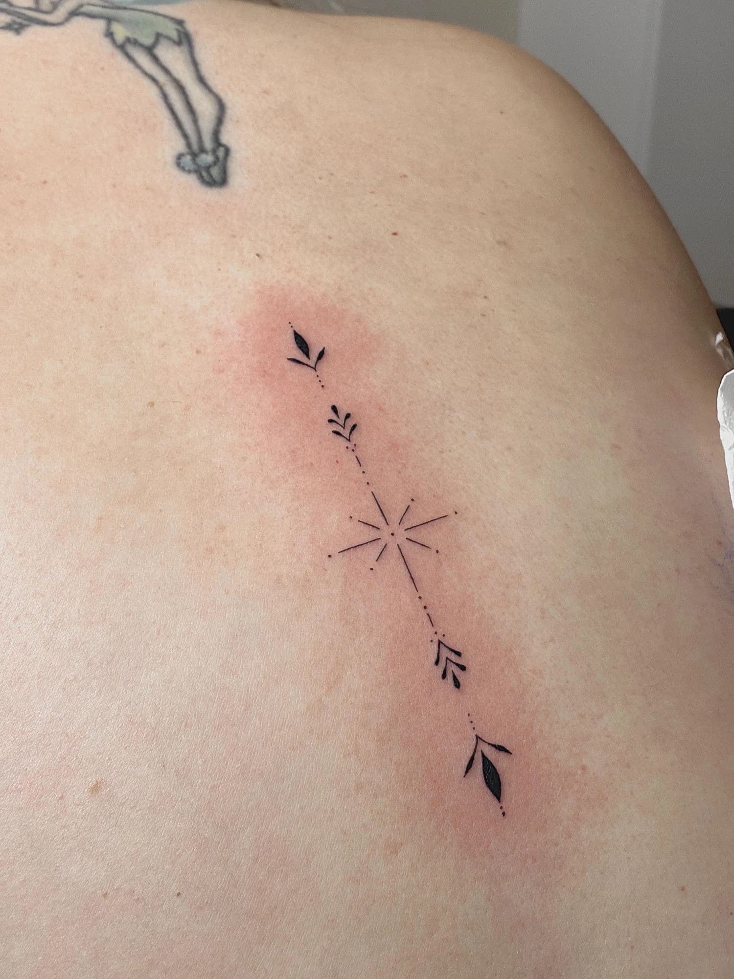 Tatuaje estrella y brújula floral en espalda